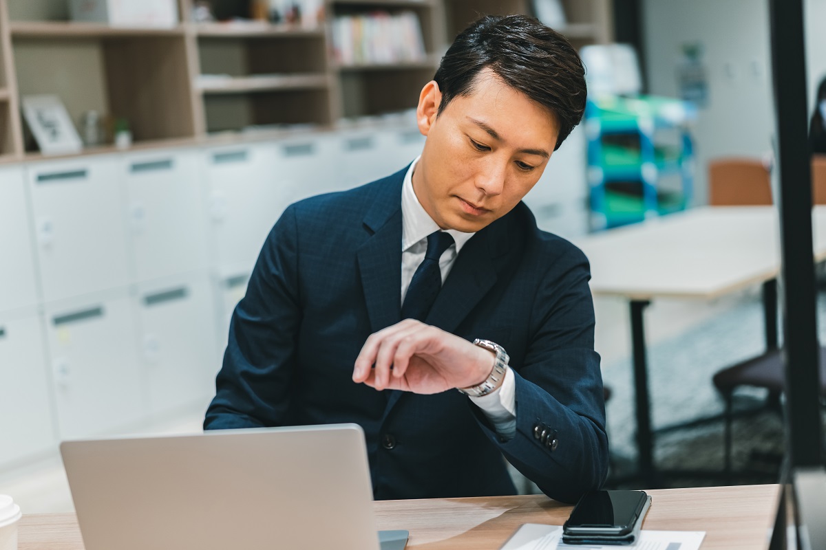 残業時間の問題を解決！長時間労働の原因を知って対策しよう（腕時計を見つめるビジネスパーソン）